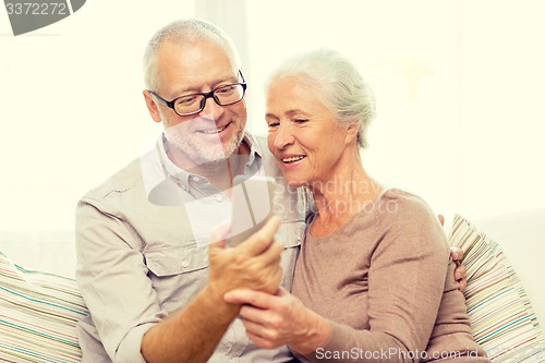 Image of happy senior couple with smartphone at home