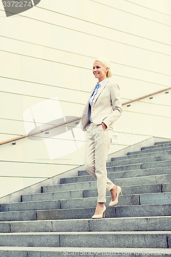 Image of young smiling businesswoman walking down stairs