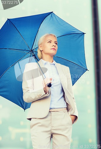 Image of young serious businesswoman with umbrella outdoors