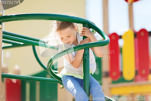 Image of happy little girl climbing on children playground