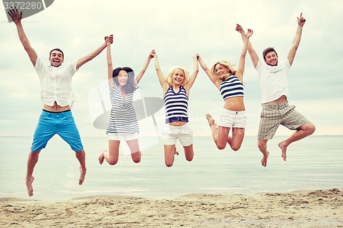 Image of smiling friends in sunglasses walking on beach