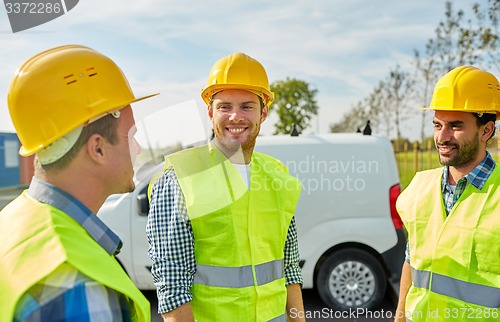 Image of happy male builders in high visible vests outdoors