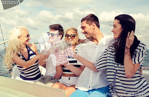 Image of smiling friends with glasses of champagne on yacht