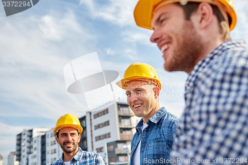 Image of group of smiling builders in hardhats outdoors