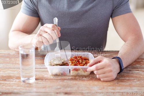 Image of close up of man with fork and water eating food