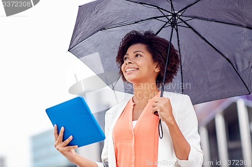 Image of businesswoman with umbrella and tablet pc in city
