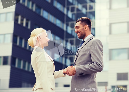 Image of smiling businessmen standing over office building