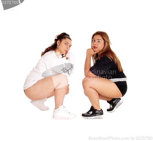 Image of Two pretty young woman crouching.