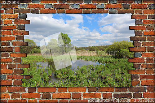 Image of broken brick wall and view to spring landscape