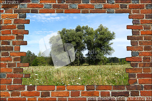 Image of broken brick wall and view to summer landscape