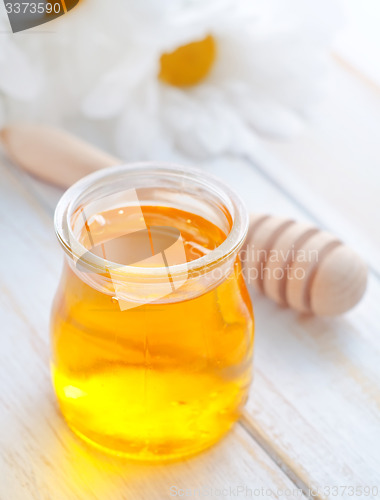 Image of fresh honey in the glass bank and camomiles