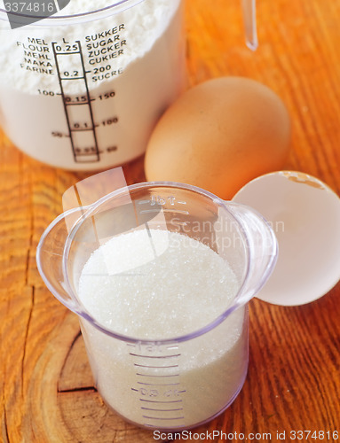 Image of Sugar, flour and raw eggs on the wooden board