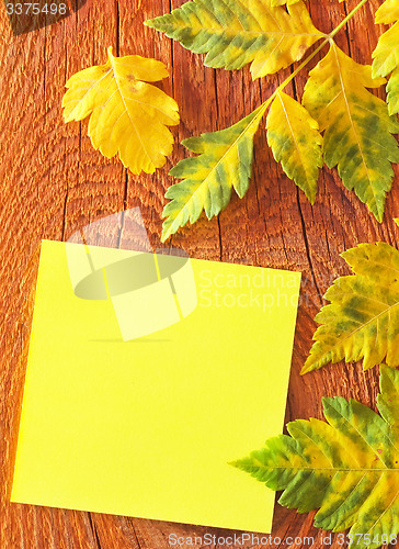 Image of note and leaves on wooden background