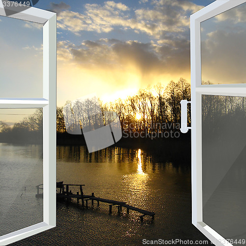 Image of window opened to the river with sunset