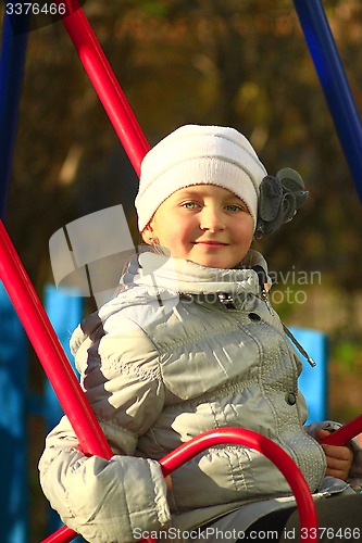 Image of little girl plays on the swing