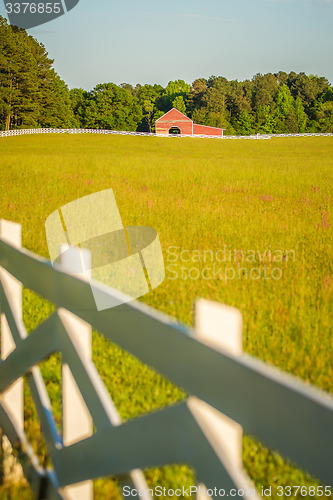 Image of  white fence leading up to a big red barn