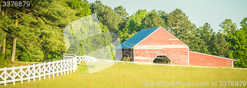 Image of  white fence leading up to a big red barn