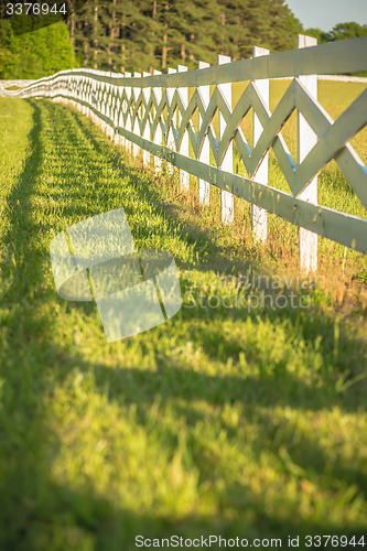 Image of  white fence leading up to a big red barn