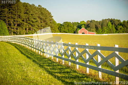 Image of  white fence leading up to a big red barn