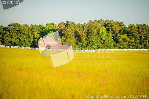 Image of  white fence leading up to a big red barn