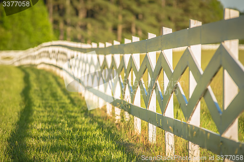 Image of  white fence leading up to a big red barn