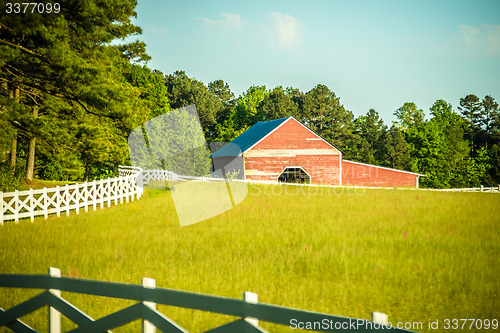 Image of  white fence leading up to a big red barn