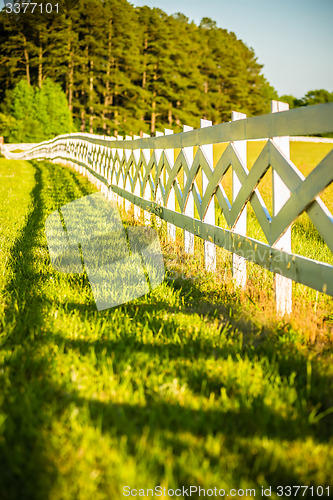 Image of  white fence leading up to a big red barn