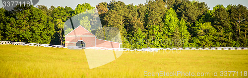 Image of  white fence leading up to a big red barn