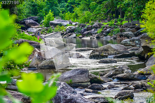 Image of broad river flowing through wooded forest