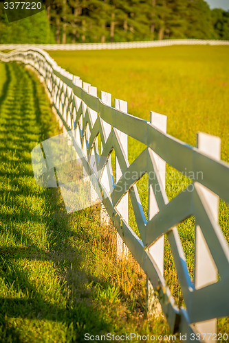 Image of  white fence leading up to a big red barn