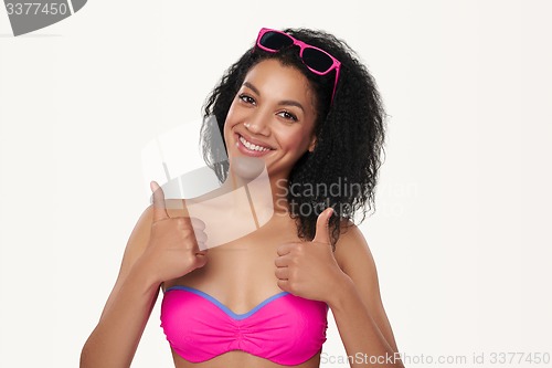 Image of Smiling woman in swimsuit gesturing thumb up