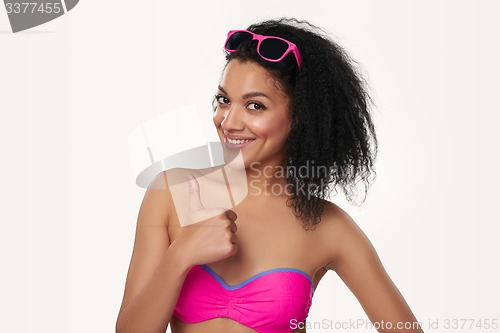 Image of Smiling woman in swimsuit gesturing thumb up