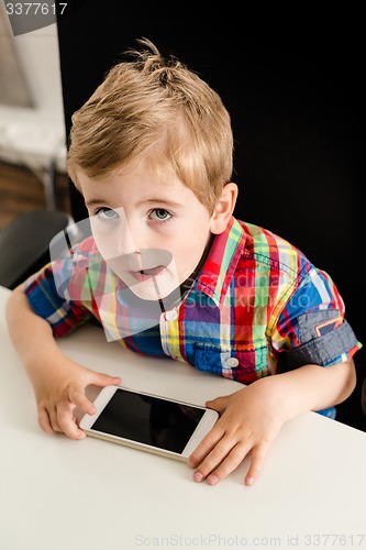 Image of Little boy plays with smartphone 