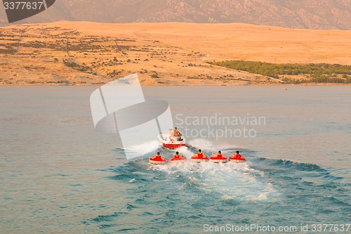 Image of Kids tube riding tawed by speedboat.