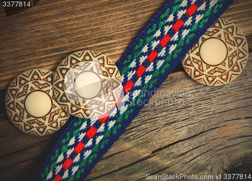 Image of three ancient buttons and varicolored vintage band