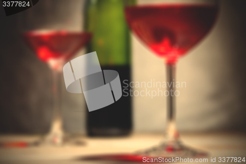 Image of red wine in two goblets and green bottle