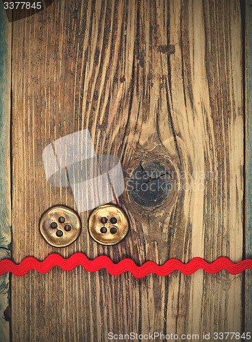 Image of still life with old red tape and two vintage buttons