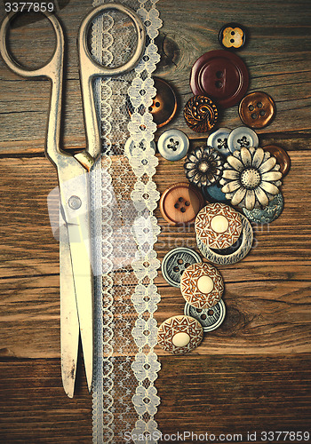 Image of aged buttons, lace and a tailor scissors
