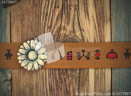 Image of vintage band with embroidered ornaments and old button flower