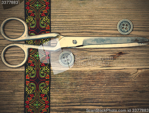 Image of embroidered tape, vintage buttons and a tailor scissors