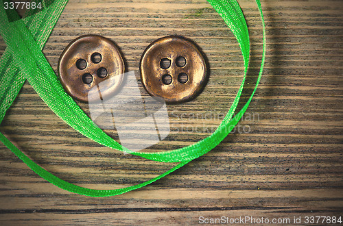 Image of still life with old green tape and two vintage buttons