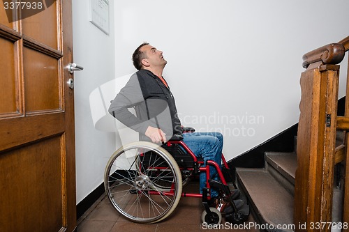 Image of man in wheelchair facing a barrier of stairs