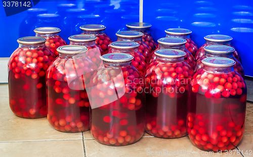 Image of Home canning: large glass cylinders with cherry compote.