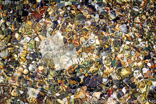 Image of Small sea stones on the seashore, covered with a sea wave.