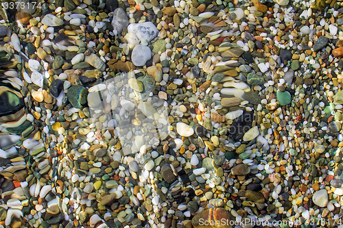 Image of Small sea stones on the seashore, covered with a sea wave.