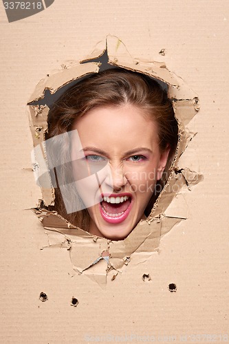 Image of Screaming girl peeping through hole in paper