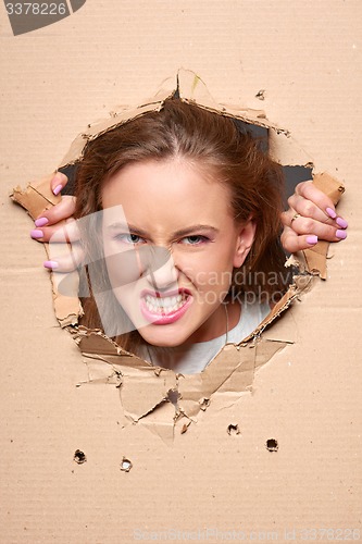 Image of Angry girl peeping through hole in paper
