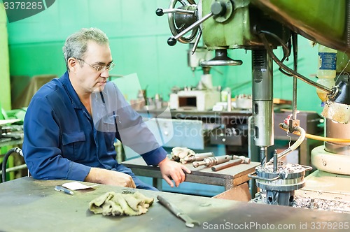 Image of Senior worker operates metalworking machine