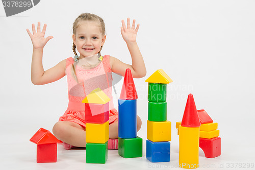 Image of Girl happily raised his hands, playing with blocks