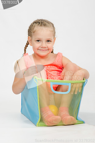 Image of Cheerful girl in a box for toys